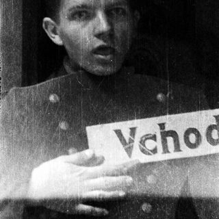 Young man in military uniform holding protest sign.