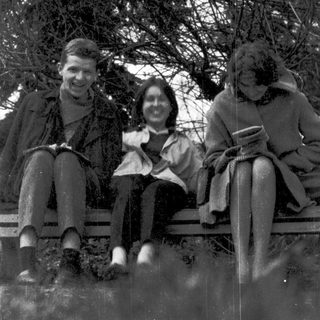 Three people sitting on a bench outdoors in winter attire.