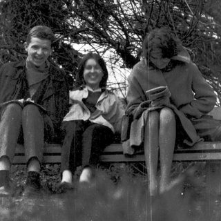 Three people sitting on a bench outdoors in winter attire.