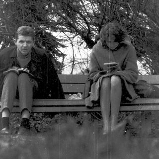 Two people sitting on a bench outdoors in winter.