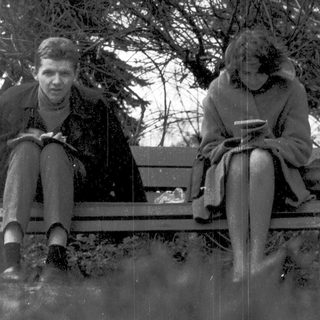 Two people sitting on a bench outdoors in winter.