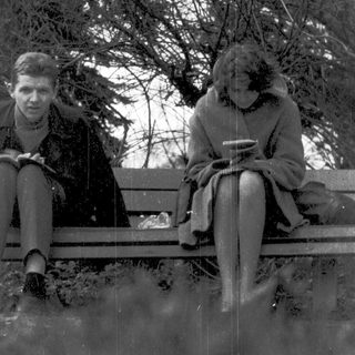 Two people sitting on a bench outdoors in winter.