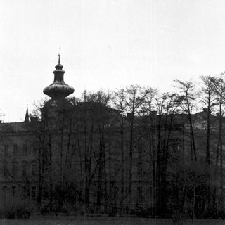 Historic building with onion dome and bare trees.