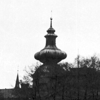 Historic building with onion dome and bare trees.