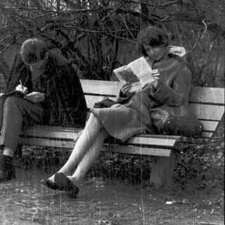 Two people reading books on a park bench.