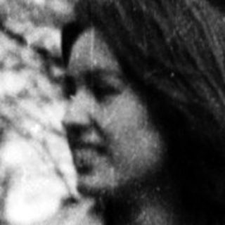 Person standing outdoors in a park-like setting.