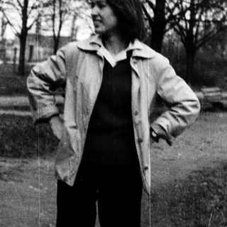 Person standing outdoors in a park-like setting.