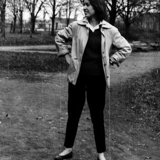 Person standing outdoors in a park-like setting.