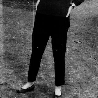 Young woman in 1960s-style outfit standing outdoors.
