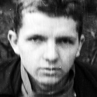 Black-and-white portrait of a young man in outdoor setting.