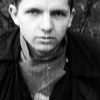 Black-and-white portrait of a young man in outdoor setting.