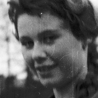 Young woman in vintage jacket outdoors, mid-20th century.