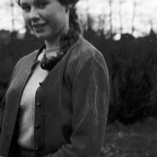 Young woman in vintage jacket outdoors, mid-20th century.