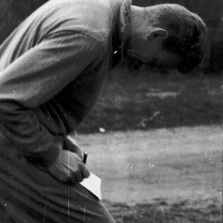 Man bending forward to inspect or place a frisbee.
