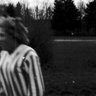 Blurred child standing outdoors near trees.