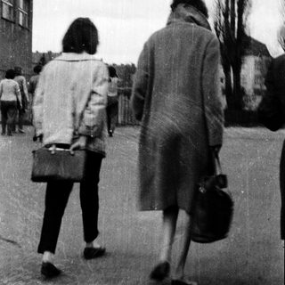 Two people walking away from camera in urban setting.