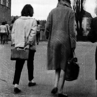Two people walking away from camera in urban setting.