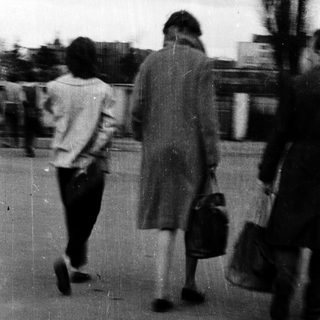 Blurred street scene of people walking outdoors.
