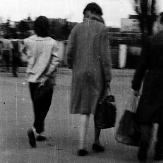 Blurred street scene of people walking outdoors.