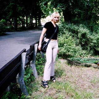 Woman standing by fence in park area.