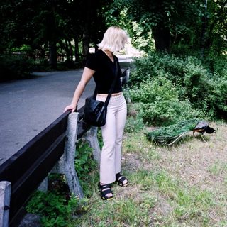 Woman observing a resting deer near fence.