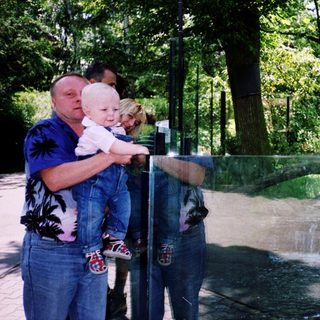 Family observing animals through transparent enclosure.