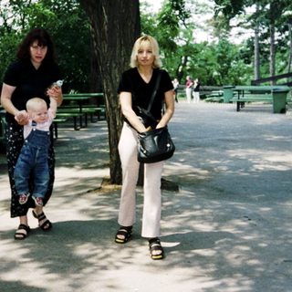 Two women walking with a child in a park.