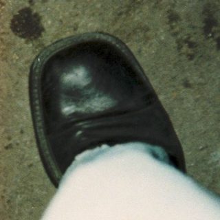 A foot in black dress shoe near a red line.