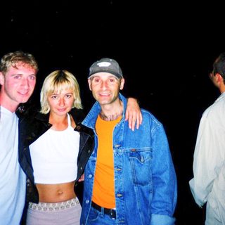 Four people posing together outdoors at night.