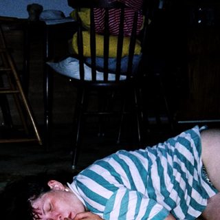 Child sleeping on floor beside adult.