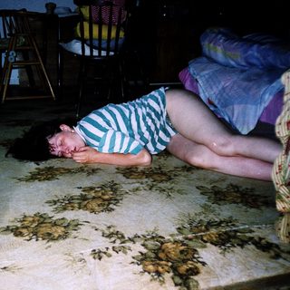 Child sleeping on floor beside adult.