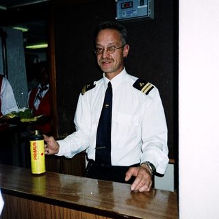 Maritime officer holding beverage at ship reception desk.