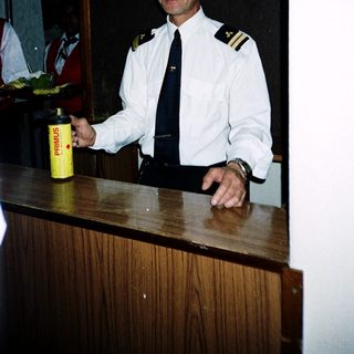 Maritime officer holding beverage at ship reception desk.