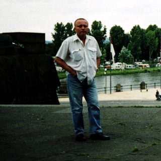 Man standing by waterfront promenade near flooded area.