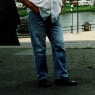 Man standing by waterfront promenade near flooded area.