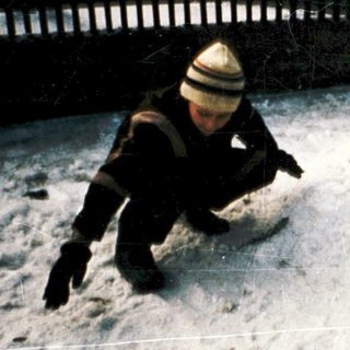 Two children building snow sculptures outdoors.