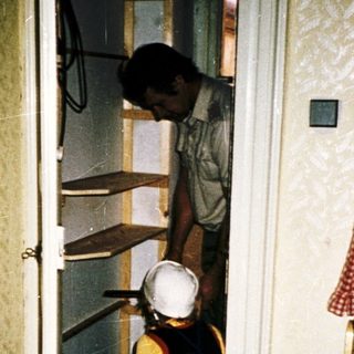 Two people organizing shelves in a kitchen.