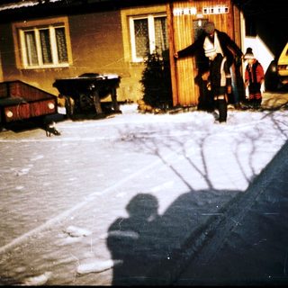 Winter scene with people carrying items near a house.