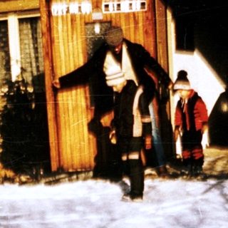 Winter scene with people carrying items near a house.