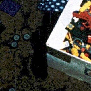 Child playing with open Lego box on carpet.