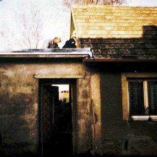 Roofer working on damaged, weathered house roof.