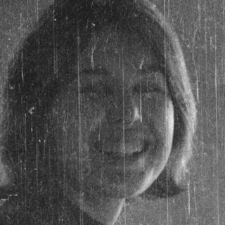 Woman sitting indoors by window during rain.