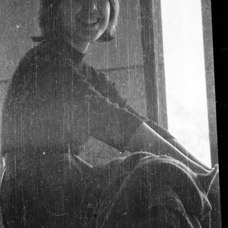 Woman sitting indoors by window during rain.