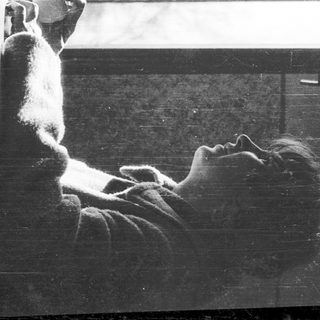 Person sitting indoors near a window, looking outside.