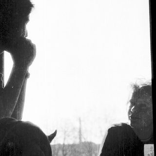 Two people sitting indoors, one resting chin on hand.