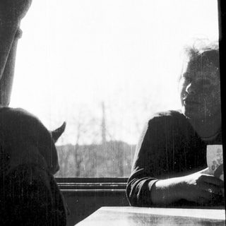 Two people sitting indoors, one resting chin on hand.