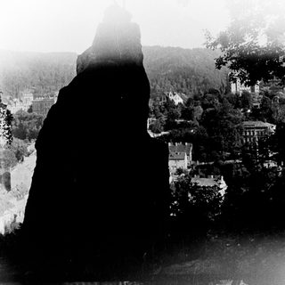 Silhouette of person overlooking misty town and hills.