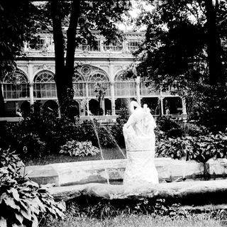 Elegant fountain with classical statues in landscaped garden.