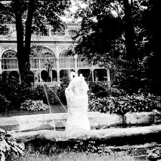 Elegant fountain with classical statues in landscaped garden.