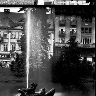 A statue of a child in a boat under a fountain.